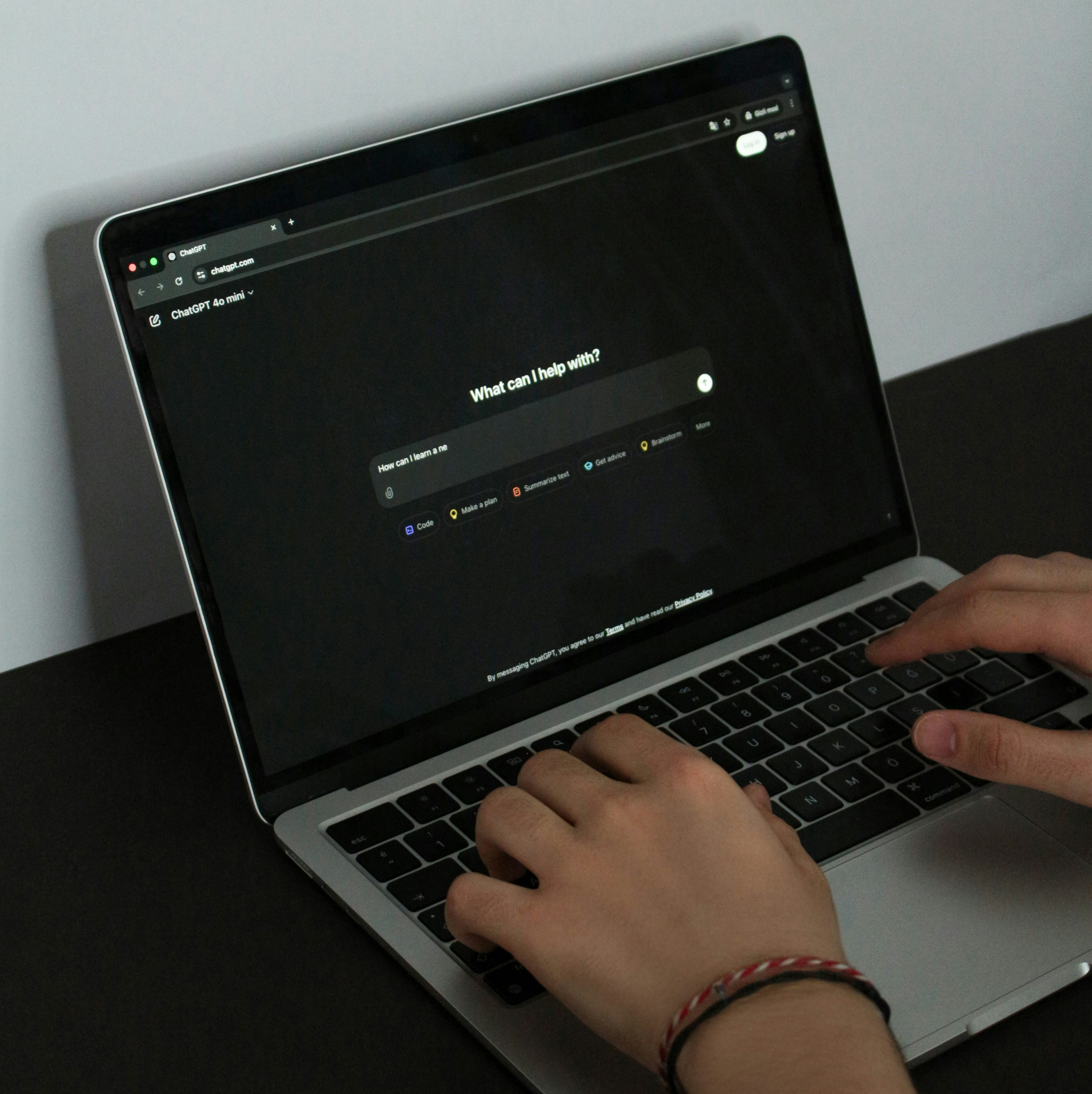 Person using laptop with "What can I help with?" in bold writting on the screen